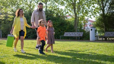 Família com crianças caminhando junta em um parque ensolarado.