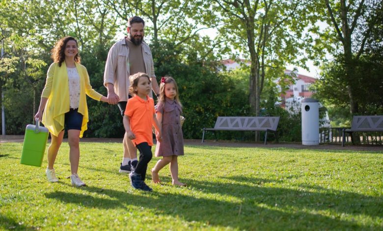 Família com crianças caminhando junta em um parque ensolarado.