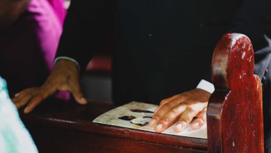 Close de mãos apoiadas em um banco durante uma cerimônia de casamento.