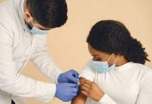 Mulher recebe uma vacina de um profissional de saúde em uma clínica.