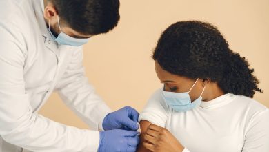 Mulher recebe uma vacina de um profissional de saúde em uma clínica.