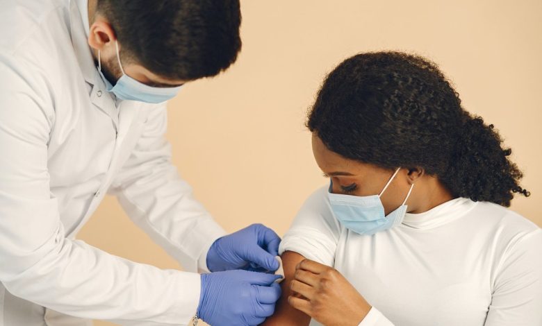Mulher recebe uma vacina de um profissional de saúde em uma clínica.