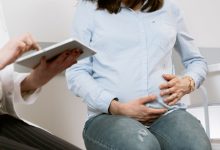 Gestante participa de uma consulta médica em ambiente de atendimento de saúde.