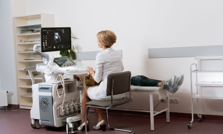 Médica realiza exame de ultrassonografia em uma paciente dentro de uma clínica.