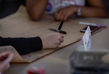 Pessoas escrevem em uma grande folha durante uma reunião colaborativa de planejamento.