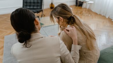 Duas mulheres sentadas em ambiente interno, conversando com empatia e oferecendo apoio uma à outra.