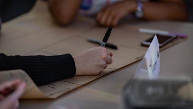 Pessoas escrevem em uma grande folha durante uma reunião colaborativa de planejamento.